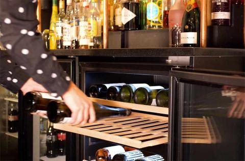 Female stocking a wine fridge in a restaurant